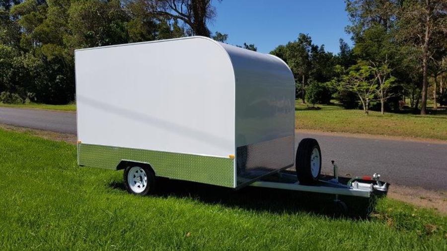 White fully enclosed cargo trailer parked on grass