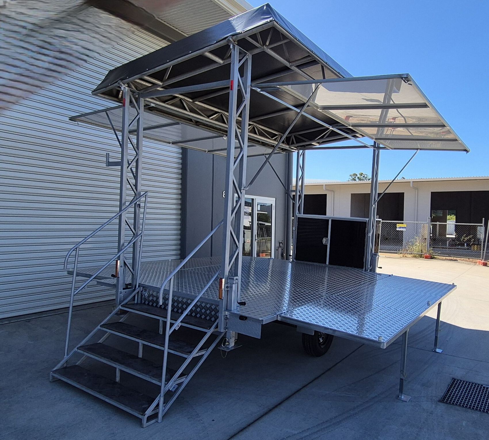 Mobile stage trailer folded out with steps and an awning roof